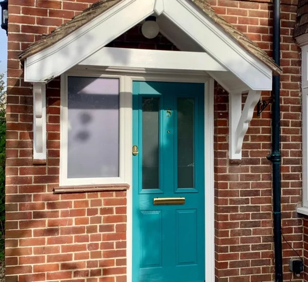 Teal composite front door installed by Keystone Glazing in West Sussex, framed by red brickwork and a white porch canopy.