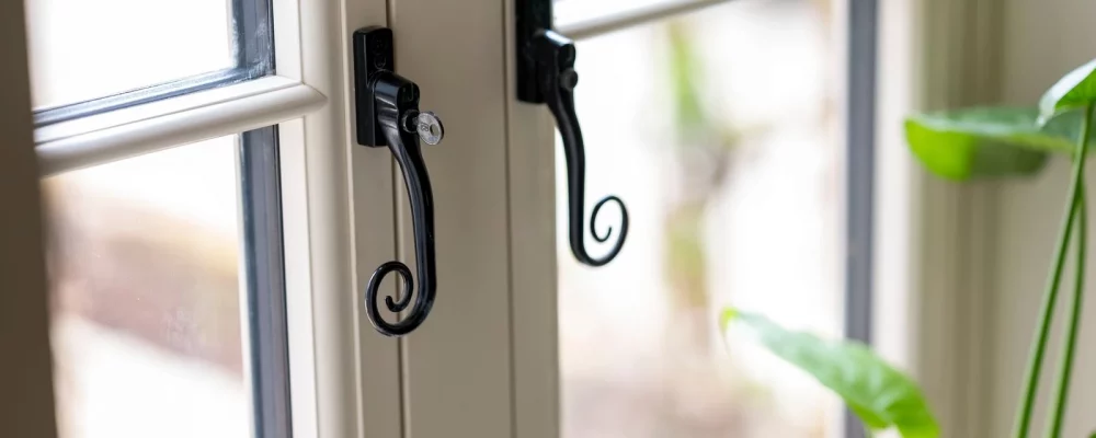 Timber effect double glazed window with black heritage-style locking handle in Chichester home.